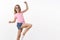 Cheerful energized and charismatic little blond girl in summer sunglasses, pink t-shirt jumping, lift leg posing