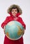 Cheerful European boy in bright red snowy down jacket with hood, holding huge globe in his hands, smiles looking at camera,