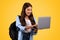 Cheerful european teen student lady with backpack, typing on laptop, chatting