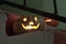 Cheerful and evil face carved from a pumpkin for the Halloween holiday. Pumpkin head smiles at the stair step. The candle burns