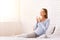 Cheerful Expectant Girl Holding Coffee Mug Sitting In Bedroom