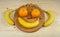 A cheerful face on a round wooden tray made of bananas, tangerines and nuts