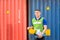 Cheerful factory worker holding hard hat, smiling man looking at camera with blurred container box background