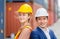 Cheerful factory worker team in hard hat smiling with arms crossed at cargo containers