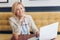 Cheerful fair-haired woman working with laptop sitting in cafe