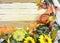 Cheerful fall or autumn border with fall leaves, nuts, sunflowers and squashes with green folded burlap and gold ribbon on a woode