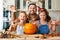 Cheerful family children and father scary gesture with pumpkin while preparing home Halloween decorations