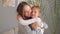 Cheerful family. Smiling brown haired mother hugging her sleepy daughter after waking up enjoying sweet moments in the morning