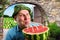 Cheerful farmer drinking watermelon