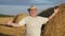 Cheerful Farmer In Hat Stands By Haystack In Rural Field