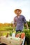 Cheerful farmer with wheelbarrow in garden