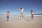 Cheerful father with children jumping on shore at beach