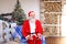 Cheerful Father Christmas congratulating on holiday by smartphon