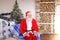 Cheerful Father Christmas congratulating on holiday by smartphon