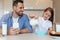 Cheerful Father And Daughter Adding Milk To Cereal In Kitchen