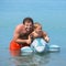 Cheerful father and son swimming in the sea on inflatable toy do