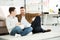 Cheerful father and teen son watching tv and holding bowl of popcorn