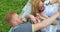 Cheerful father is tickling his beautiful smiling wife and their little son while lying on the plaid during the picnic