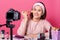 Cheerful female beautician uses cosmetic brush for applying powder, records viceo content for her blog, wears headband and casual