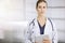 Cheerful female doctor standing in sunny clinic. Portrait of friendly smiling woman-physician. Medicine concept