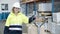 Cheerful female employee pulling trolley with boxes in stock.