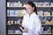 Cheerful female expert pharmacist is making notes while standing