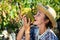 Cheerful female farmer tasting ripe grapes in vineyard