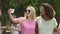 Cheerful female friends dancing to music at summer party, taking selfie on phone