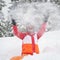 Cheerful female having fun in the snow, throwing it up above