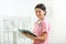 Cheerful female physician with clipboard at office