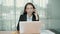 Cheerful female professional in office suit using laptop