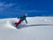 Cheerful female snowboarder sprays fresh powder snow while riding off-piste.