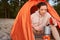 Cheerful female traveler making hot drink during camping