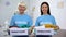 Cheerful female volunteers holding donation boxes, humanitarian aid, assistance