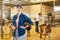 Cheerful female working with hay and straw in barn on goat farm