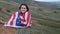 Cheerful female wraps in USA flag standing on hill