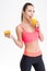 Cheerful fitness girl drinking juice and holding half of orange