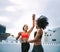 Cheerful fitness women giving high five while jogging on rooftop