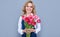 cheerful flower seller woman in apron with spring tulip flowers on grey background