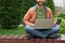 Cheerful freelancer sitting with laptop with crossed legs.