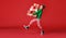 Cheerful funny child in Christmas elf costume with gifts on   red background