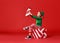 Cheerful funny child in Christmas elf costume with gifts on   red background