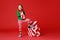 Cheerful funny child in Christmas elf costume with gifts on   red background