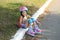 A cheerful funny laughing girl with pink pigtails in a protective helmet and roller skates sat down to rest after training.