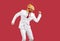 Cheerful funny man in rubber mask of chicken and in white formal suit dancing on red background.