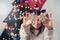 Cheerful funny woman cover her eyes with x-mas gingerbread snowflake shaped cookies and having fun near alternative christmas tree