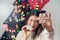 Cheerful funny woman showing to camera x-mas gingerbread snowflake shaped cookies near alternative christmas tree. Depth of field