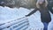 Cheerful funny young woman wipes snow from a bench in a winter park. Slow motion