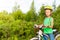 Cheerful girl with braids in helmet holds bike