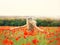 Cheerful girl with curly blond hair dances in a huge poppy field alone, her hair is flying because of the wind flow